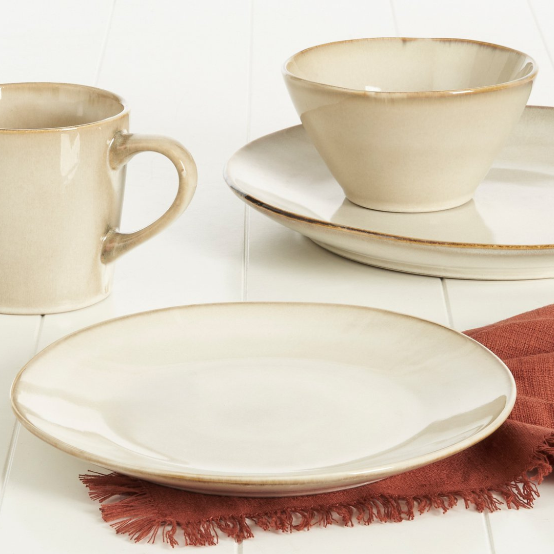 Beigefarbenes Keramikgeschirr-Set mit Teller, Schale und Tasse auf weißer Oberfläche