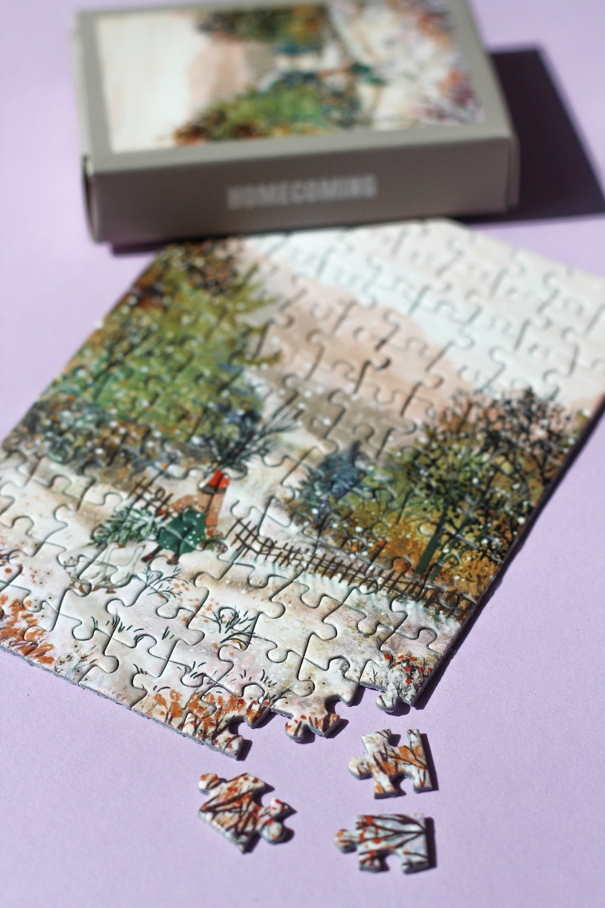 Fast fertig gelegtes Minipuzzle Homecoming mit drei losen Teilen und Schachtel im Hintergrund