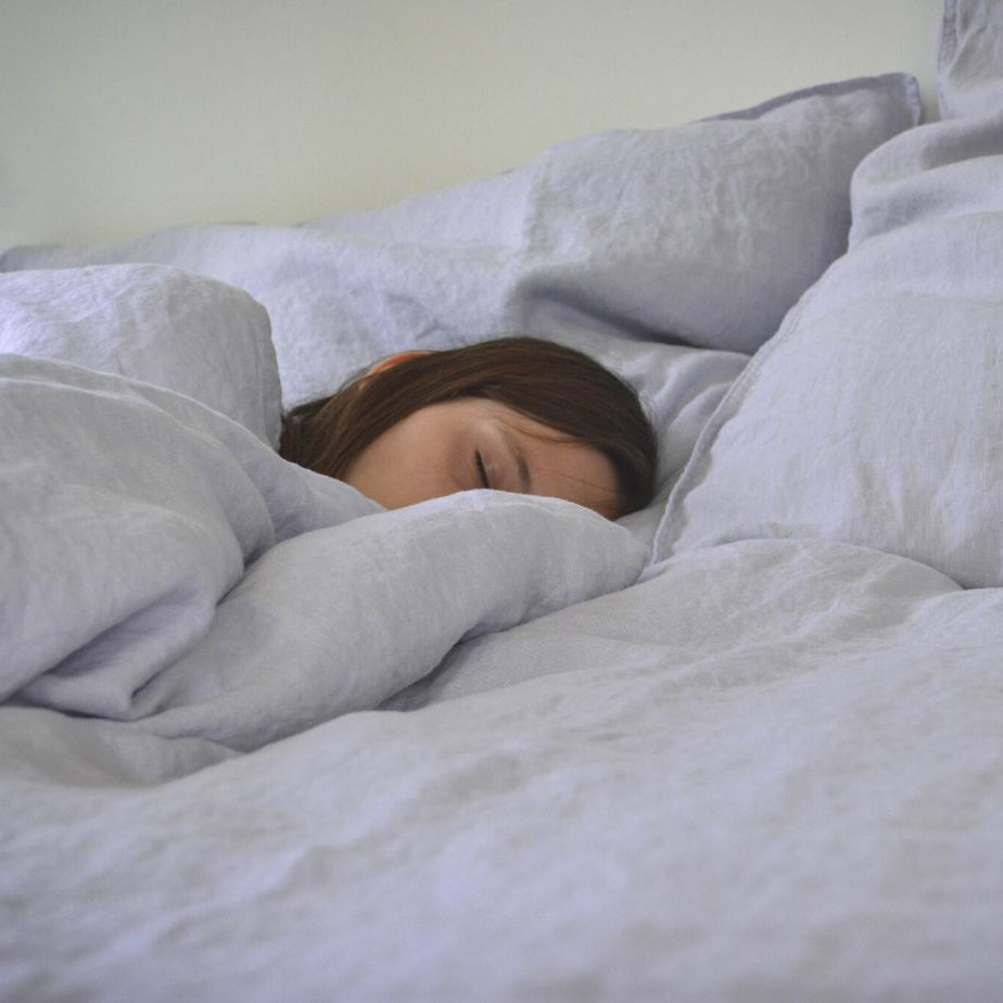 Person schläft in heller Bettwäsche aus 100 % Hanf in der Farbe Cool Spring