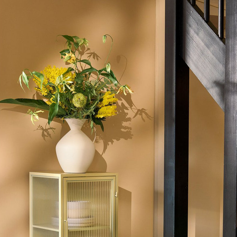 Metallvase mit Henkel in Creme mit frischen Blumen