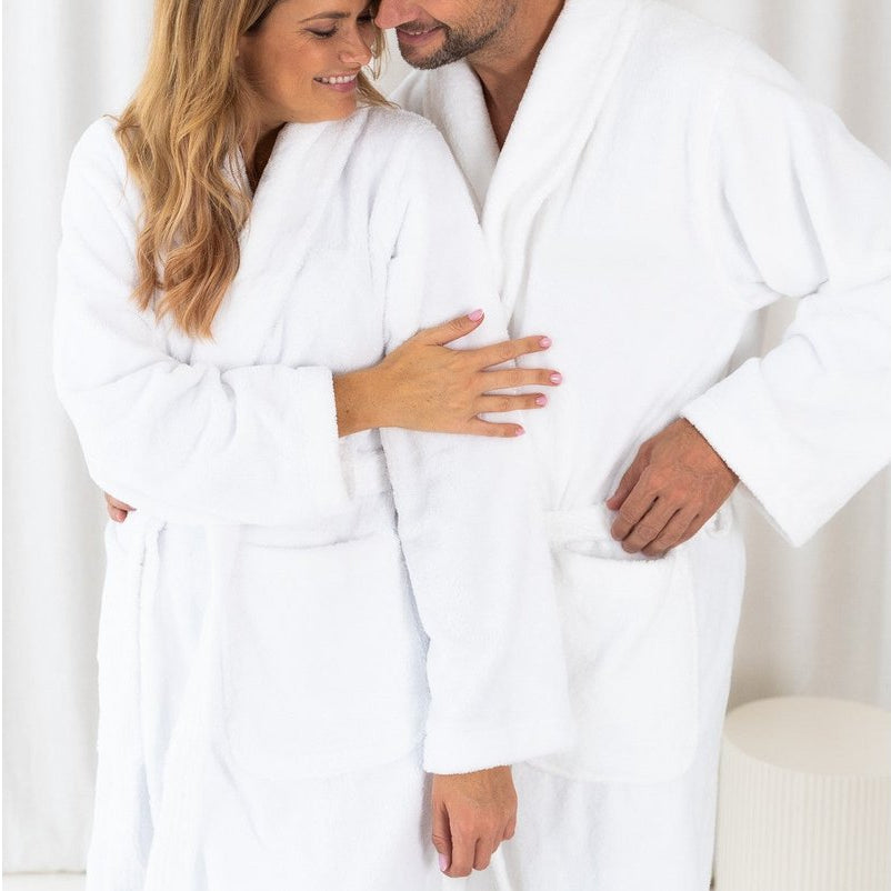 Paar trägt weiße, weiche Teddy-Bademäntel aus Fleece und Baumwolle und lächelt sich an